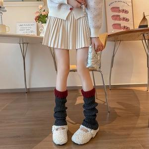 Détail de jambières en tricot gris foncé avec bord rouge et Mary Janes en peau de mouton