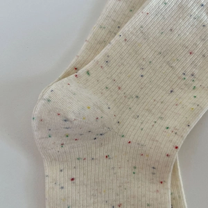 Vue macro d'une chaussette en maille côtelée crème avec fil moucheté coloré