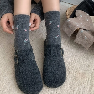 Detail of wool mule shoes with buckle and floral embroidered grey thermal socks