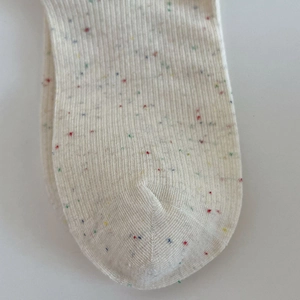 Gros plan détaillé de chaussettes en maille crème avec points colorés et texture côtelée