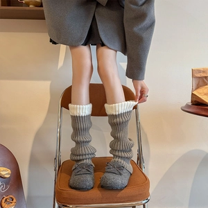 Détail de jambières en maille gris et blanc avec texture côtelée et ballerines à nœud