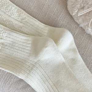 Detailed close-up showing the soft knit texture and ribbed pattern of creamy white socks