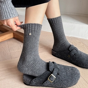 Detail of dark grey wool socks with rib knit texture and a metal button decoration