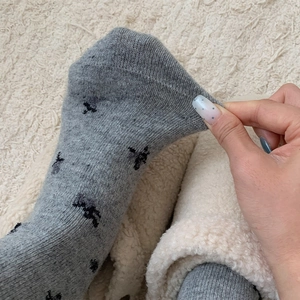 Close-up of gray floral wool socks showing elastic stretch and warm knitted texture