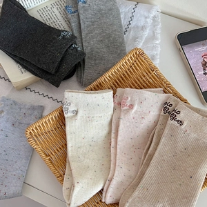 Détail des chaussettes en tricot côtelé avec broderie de lettres et fils mouchetés colorés