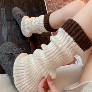 Détail de jambières en tricot crème et marron avec revers côtelés et chaussons douillets