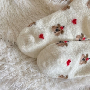 Nahaufnahme dicker cremefarbener Thermosocken mit süßem Bären und rotem Herzmuster