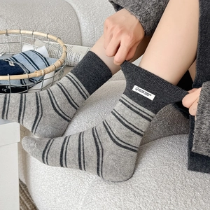 Detail of grey striped crew socks showing elastic stretch and woven label design