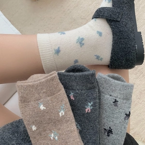 Detail of warm wool blend socks with delicate floral embroidery in various autumn colors