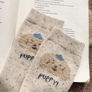 Détail du tricot de chaussettes en laine beige avec broderie pelucheuse de chiot