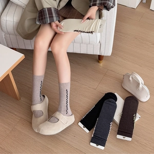 Close-up of wool ruffle trim socks in khaki, black, and grey with vertical wave line details