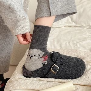 Detail of wool socks with white cartoon dog pattern and grey felt buckle clogs shoes