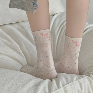 Gros plan de chaussettes roses mouchetées avec broderie Magic Bear et maille côtelée