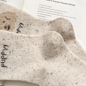 Détail de chaussettes en laine beige avec motif chiot et texture tricotée douce