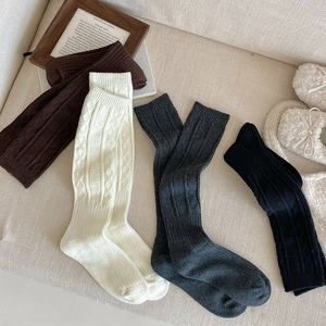Detailed knit texture of grey argyle knee-high socks in brown, white, and black colors