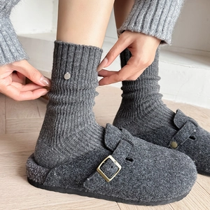 Thick wool socks with shell buttons paired with grey felt mule slippers in a cozy set
