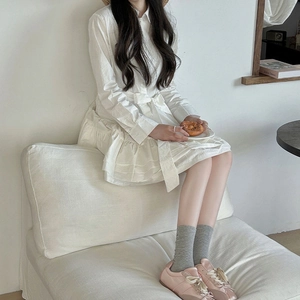 Détail de la robe chemise blanche en coton avec lien à la taille et ourlet à volants