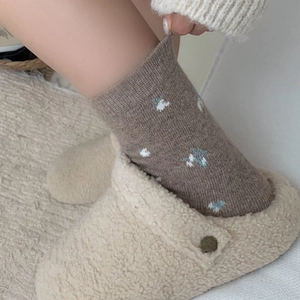 Warm floral wool socks with white fleece slippers on a textured carpet setting