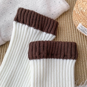 Détail de jambières en tricot blanc à côtes avec revers marron et texture moelleuse