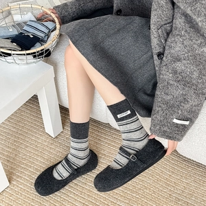 Close-up of grey striped socks with white fabric label and wool Mary Jane shoes