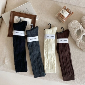 Close-up of thick knit knee socks in four colors with textured vertical stripes and wave edges