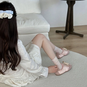 Détail de baskets en satin rose avec chaussettes à fleurs et barrette à nœud sur un tapis