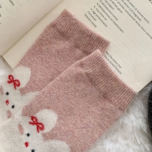 Close-up of pink knit socks featuring cute cartoon rabbit patterns with warm wool texture