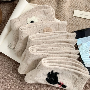 Détail de chaussettes en laine beige avec broderies d'animaux et texture