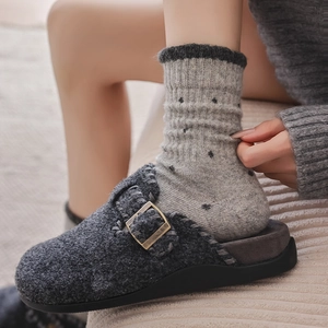Detail of grey wool felt clogs with bronze buckle and handcrafted cross stitching detail