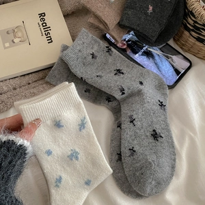 Macro view of thick floral wool socks featuring intricate knit textures and warm patterns