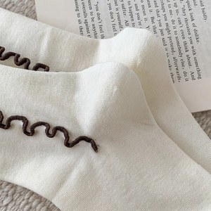 Detail of cream rib-knit wool socks with brown ruffled edges on vintage book background