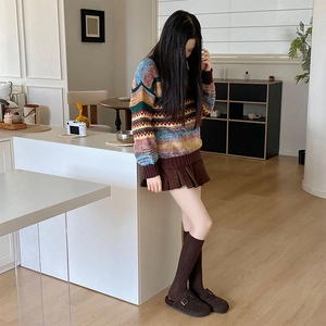 Detail view of grey Argyle knee-high socks paired with retro knitted sweater and brown skirt