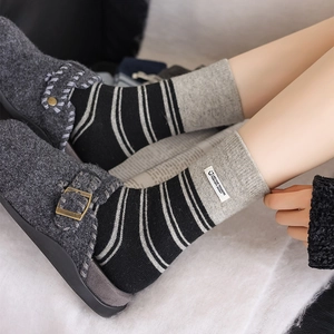 Detail of gray striped knitted socks with decorative fabric label and ribbed cuffs