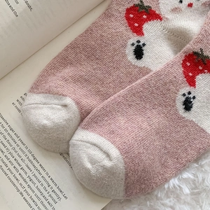 Detailed close-up of pink and white cartoon socks with bear and strawberry embroidery