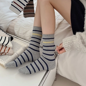Detail of ribbed knit crew socks with grey and blue stripes and yellow stitching accents