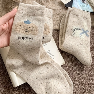Gros plan de chaussettes en laine beige avec mignons motifs brodés de chiot et chaton