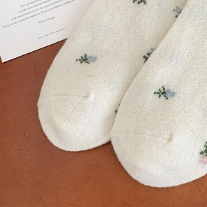 Macro shot of white knitted wool socks with blue and pink floral embroidery patterns