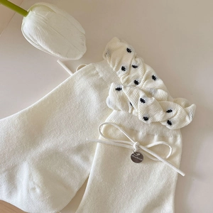 Detail von Strickstrümpfen mit Rüschensaum, schwarzen Punkten und Handmade-Silberanhänger