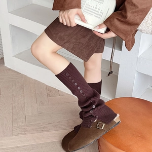 Detail view of dark brown knitted leg warmers with vintage buttons and vertical stripes