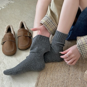 Detailed texture of gray wool blend ribbed socks paired with brown fuzzy slippers