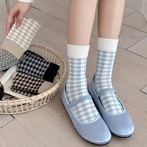 Blue and white checkered crew socks paired with Mary Jane flats on a light wood floor