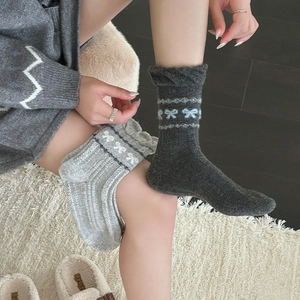 Detail von Fair-Isle-Wollsocken mit weißen Schleifenmustern und Rippbündchen für den Winter