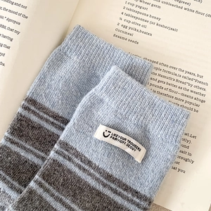 Detailed knit texture of light blue striped crew socks with white label and cozy feel