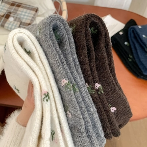 Detail showing thick wool socks with delicate pink floral embroidery in vintage style