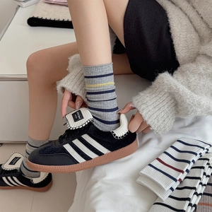 Detail of pink and grey striped cotton socks paired with classic black sneakers