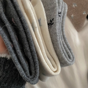 Detailed macro shot of thick knit wool socks featuring cute bear embroidery in grey and white
