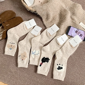 Détail de cinq paires de chaussettes en laine beige avec broderie animale et côtes