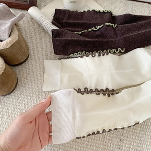 Detail of wool knit socks with ruffled edges in dark coffee and creamy white