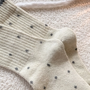 Close-up of cream wool blend socks with grey polka dots and ribbed knit texture
