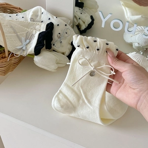 Detailansicht von cremefarbenen Rüschensocken mit Punkten und kleiner Schleife